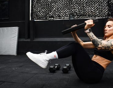 A determined woman performs a core workout in an indoor gym setting.